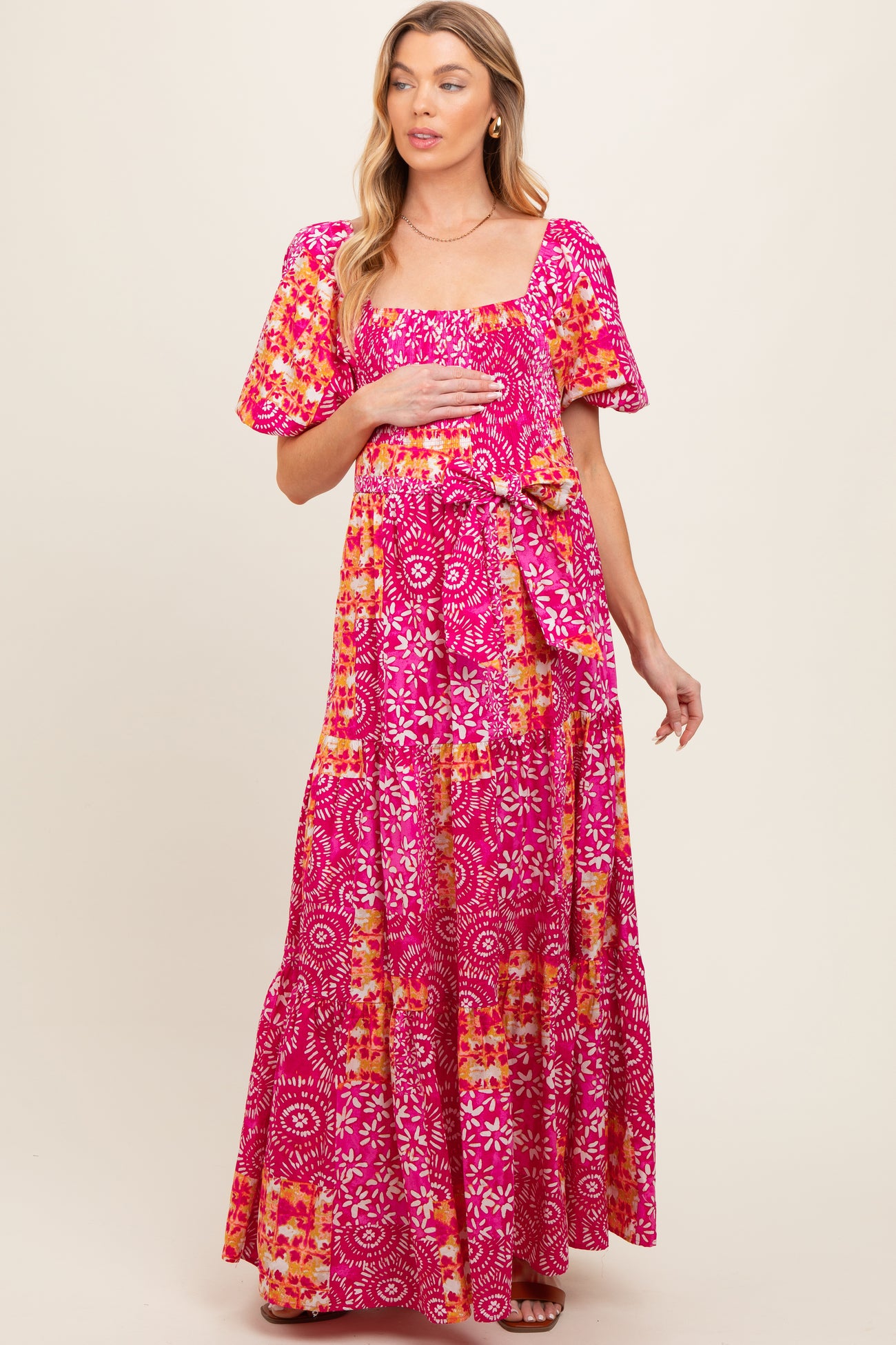 woman wearing a pink floral maternity maxi dress and holding her baby bump