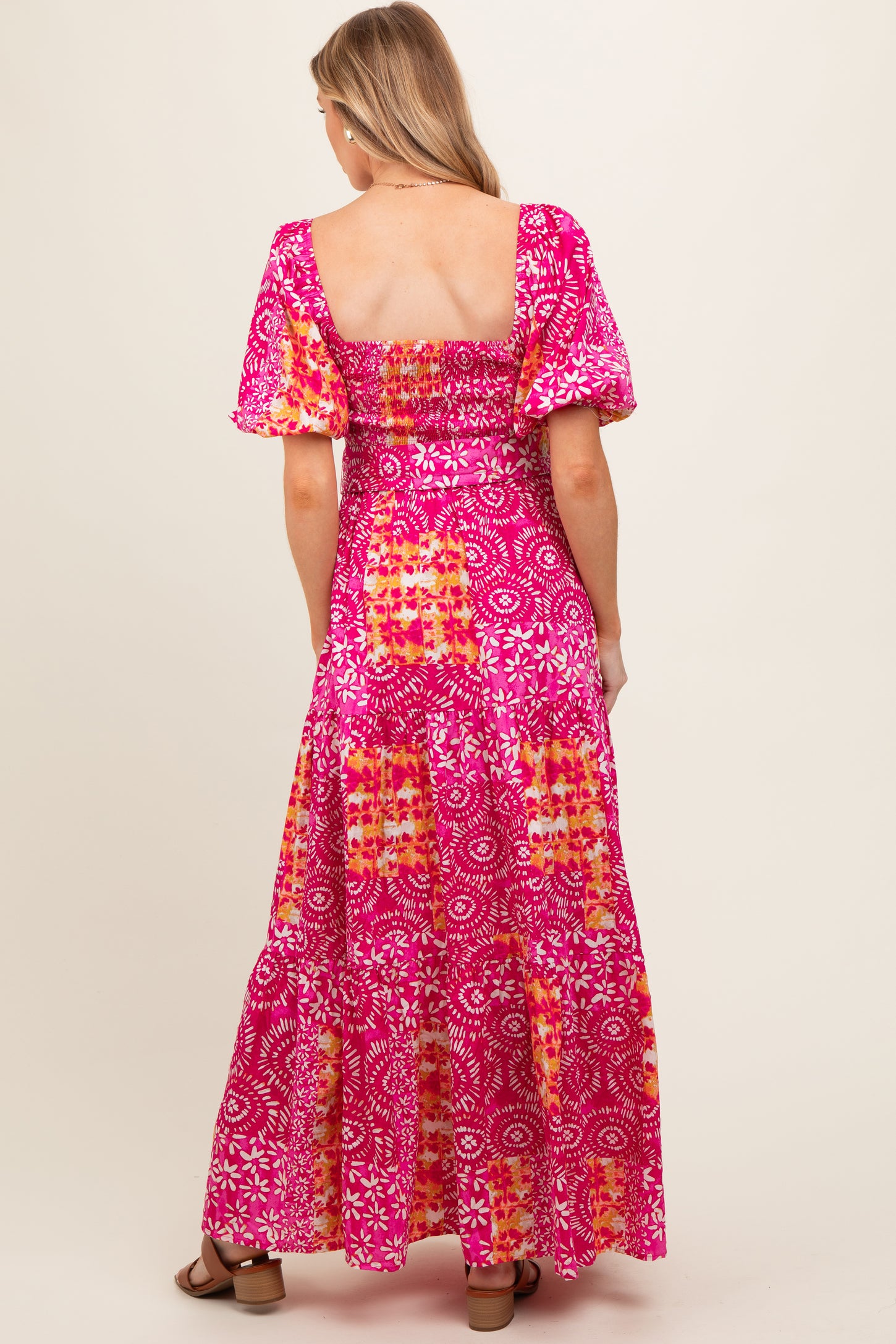 woman wearing a pink floral maternity maxi dress with puff sleeves and a smocked back design