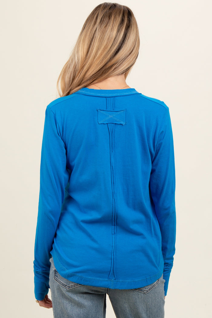 woman wearing a vibrant blue long sleeve maternity top, showing the back view with a simple design detail