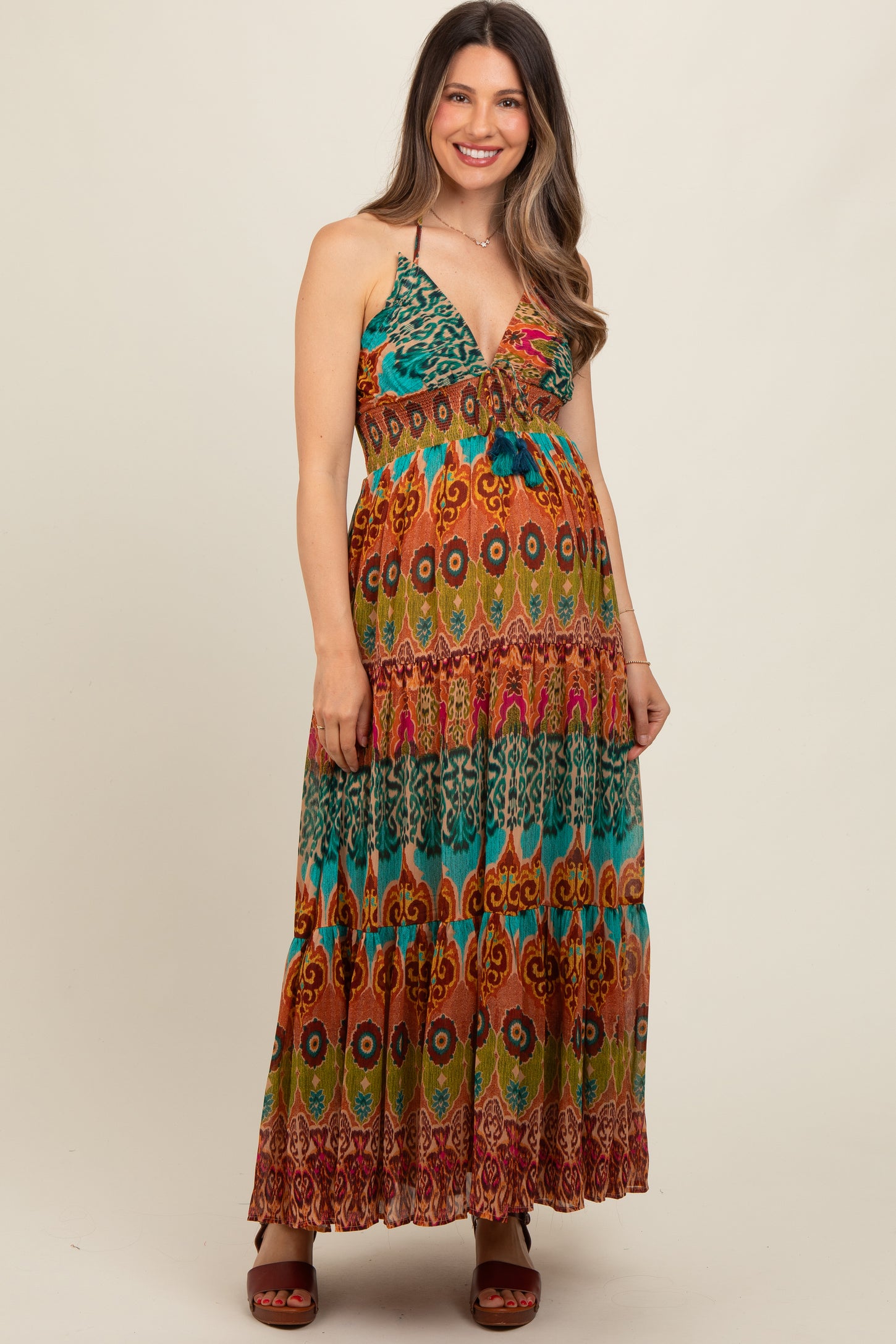 woman wearing a colorful bohemian maxi dress with a plunging neckline and a visible baby bump