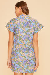 woman wearing a floral print short sleeve dress in pastel colors, showing the back view