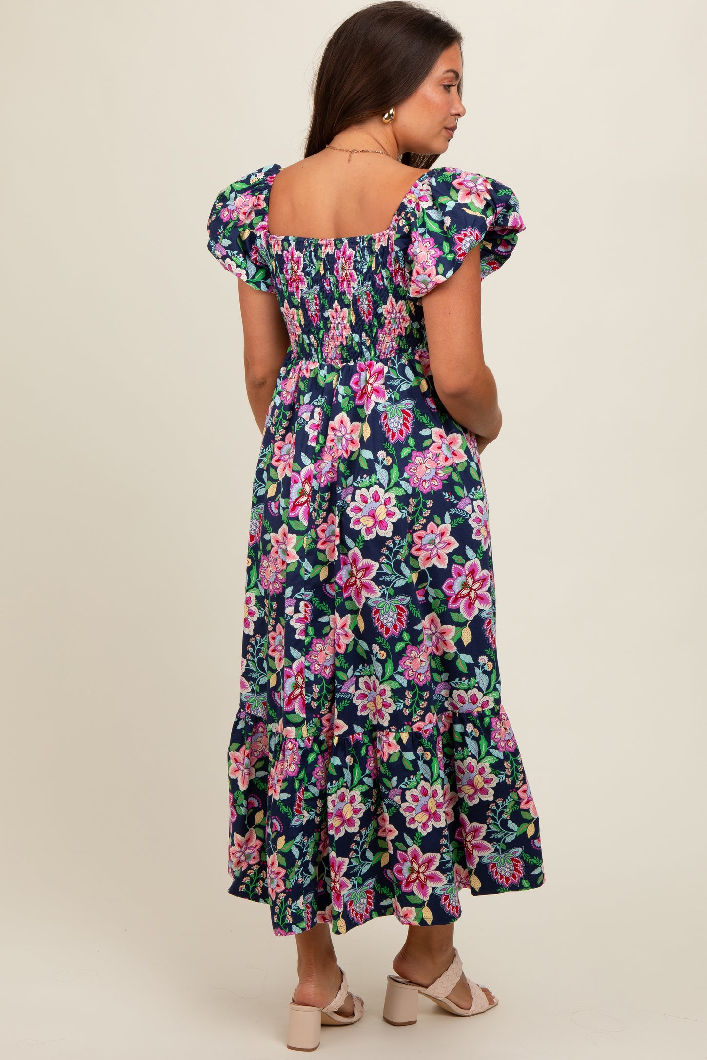 woman wearing a floral print maternity maxi dress with puff sleeves and a ruffled hem