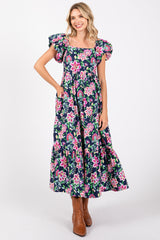 woman wearing a floral print maxi dress with puff sleeves and a tiered skirt, paired with brown ankle boots