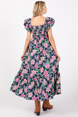 woman wearing a floral maxi dress with puff sleeves and a smocked back, showing a flowy tiered skirt.
