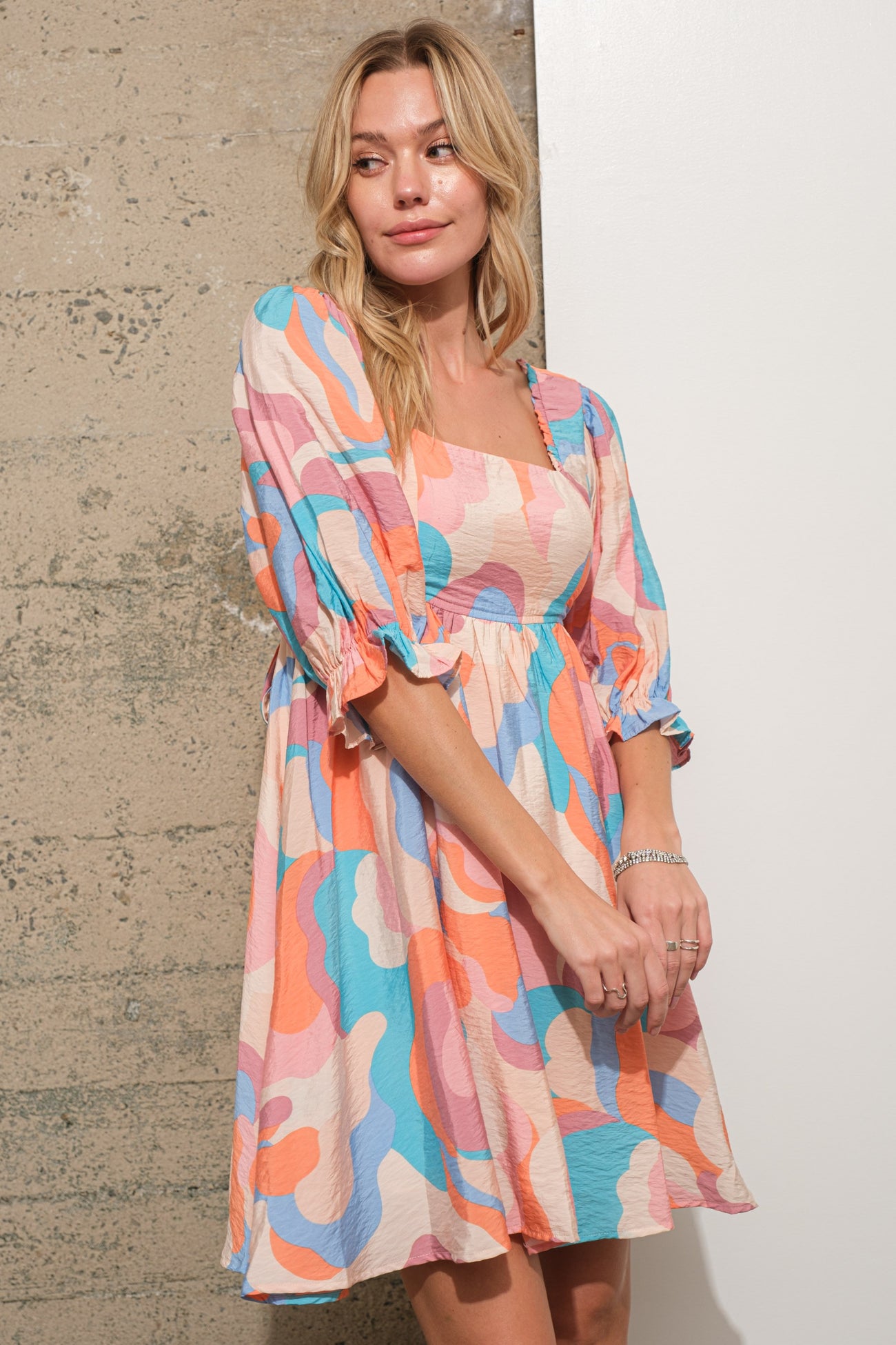 woman wearing a colorful patterned short sleeve mini dress with a square neckline and puff sleeves