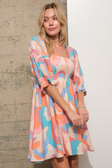 woman wearing a colorful patterned short sleeve mini dress with a square neckline and puff sleeves
