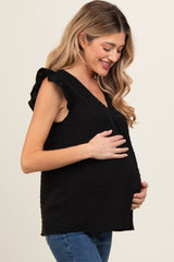 woman wearing a black maternity top with ruffled sleeves and holding her baby bump