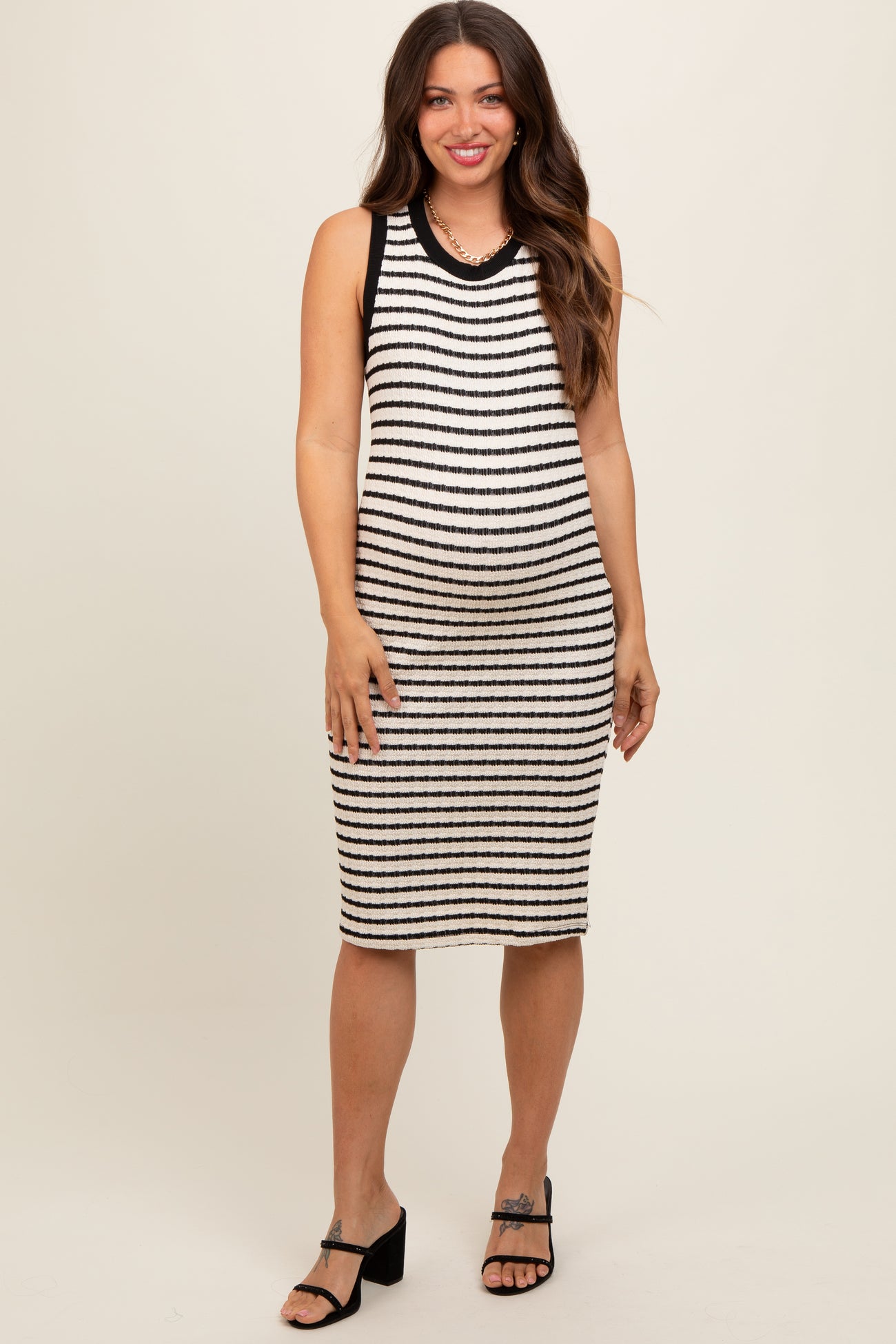 woman wearing a black and white striped maternity dress with a fitted silhouette and a round neckline, showing a baby bump