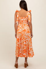 woman wearing an orange floral maternity dress with tie straps and a smocked bodice, showing her back