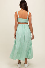 woman wearing a green and white striped maternity maxi dress with a smocked bodice and spaghetti straps