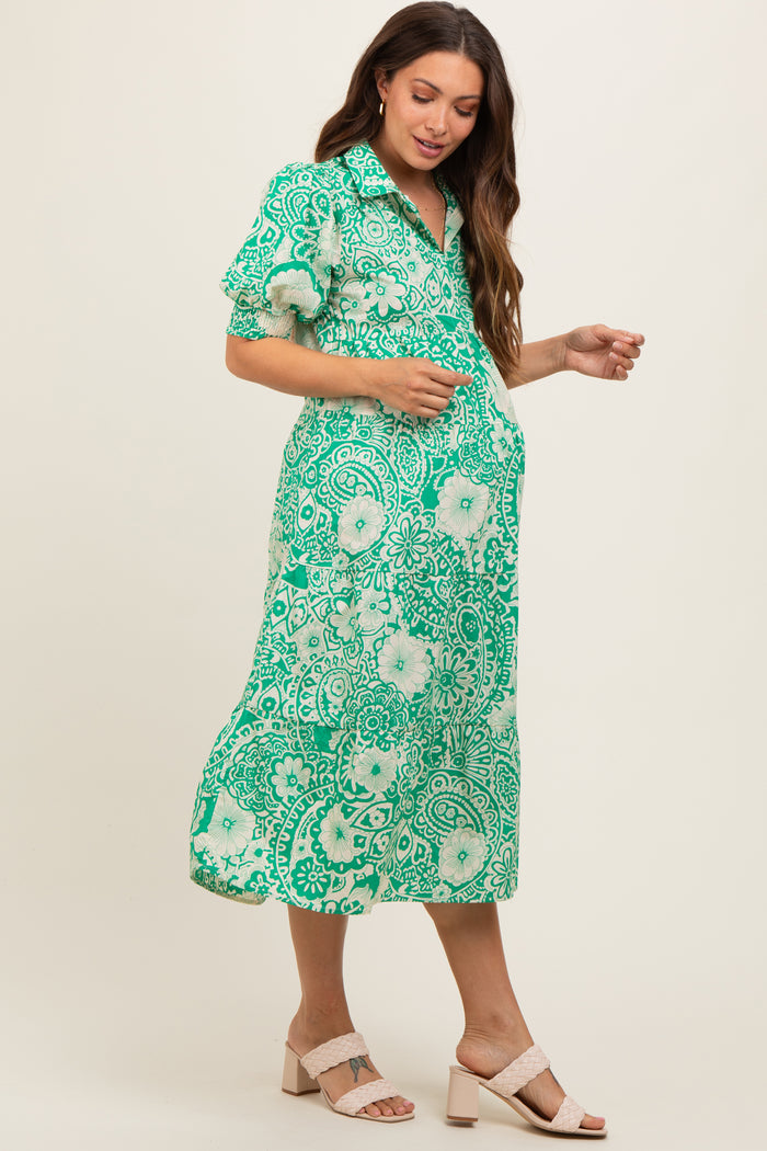 woman wearing a green floral print maternity dress with short sleeves and a flowy silhouette, showing her baby bump