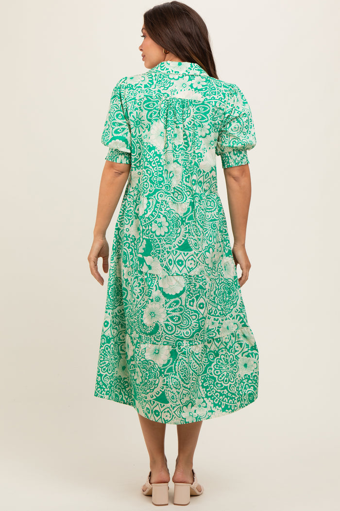 woman wearing a green floral print maternity dress with puff sleeves and a midi length, showing a baby bump from behind