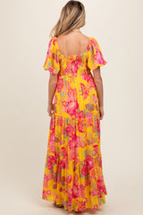 woman wearing a yellow floral maternity maxi dress with puff sleeves and a back smocked detail
