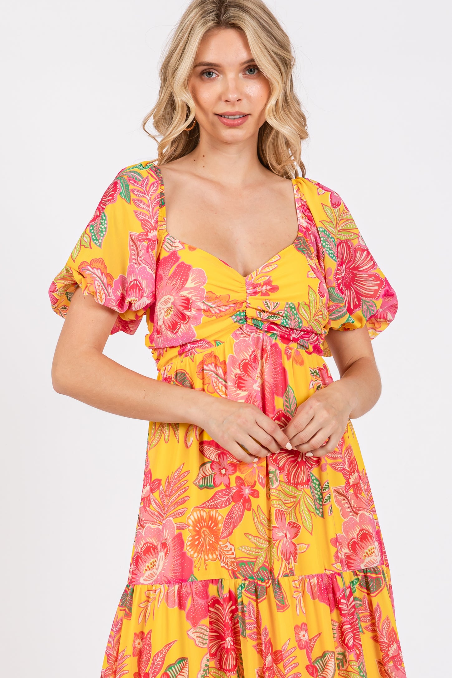 woman wearing a bright yellow floral maxi dress with puff sleeves and a sweetheart neckline