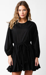 woman wearing a black long sleeve dress with a tie waist and ruffled hem