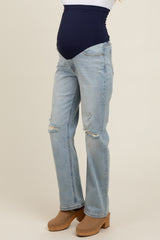 woman wearing light blue distressed maternity jeans with a navy blue over-the-belly waistband and tan clogs