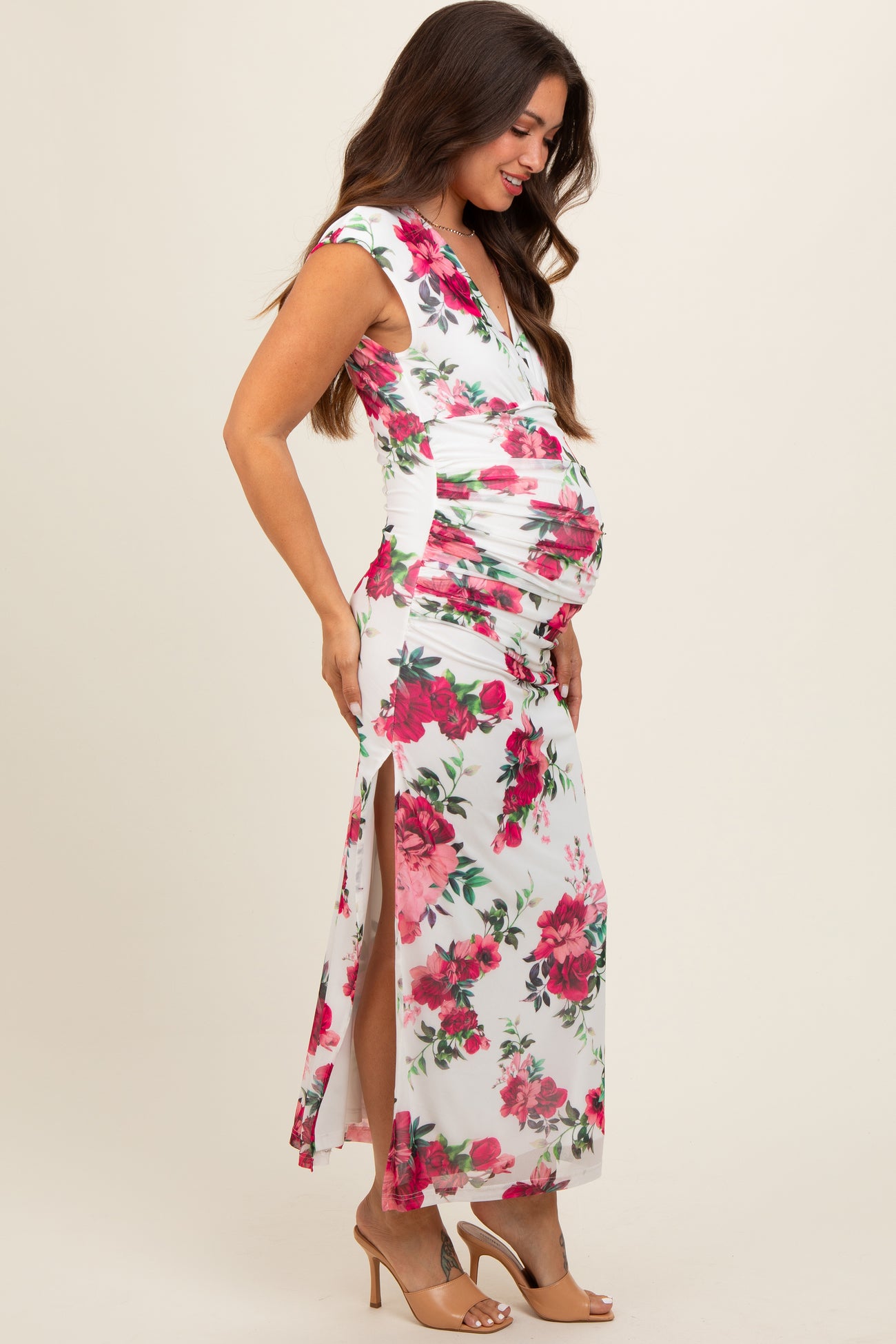 woman wearing a white floral maternity maxi dress with side slits and a visible baby bump