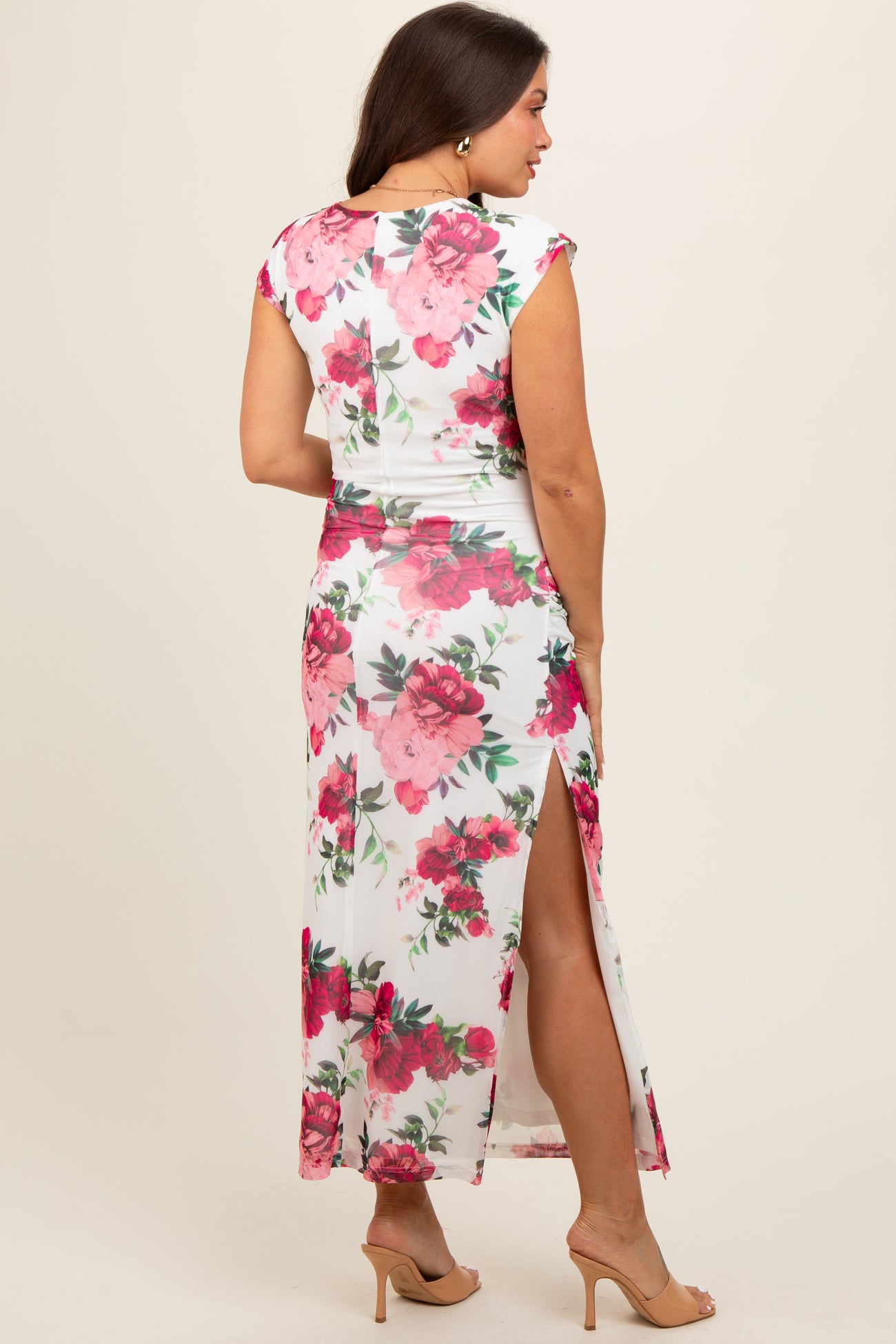 woman wearing a floral maternity maxi dress with a high slit and cap sleeves, showing a baby bump