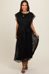 woman wearing a black maternity dress with short flutter sleeves and a tied waist detail, posing with a smile