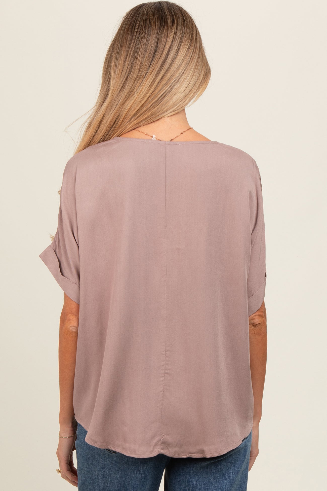 woman wearing a mauve short sleeve maternity top, featuring a relaxed fit and round hem with a smooth back design
