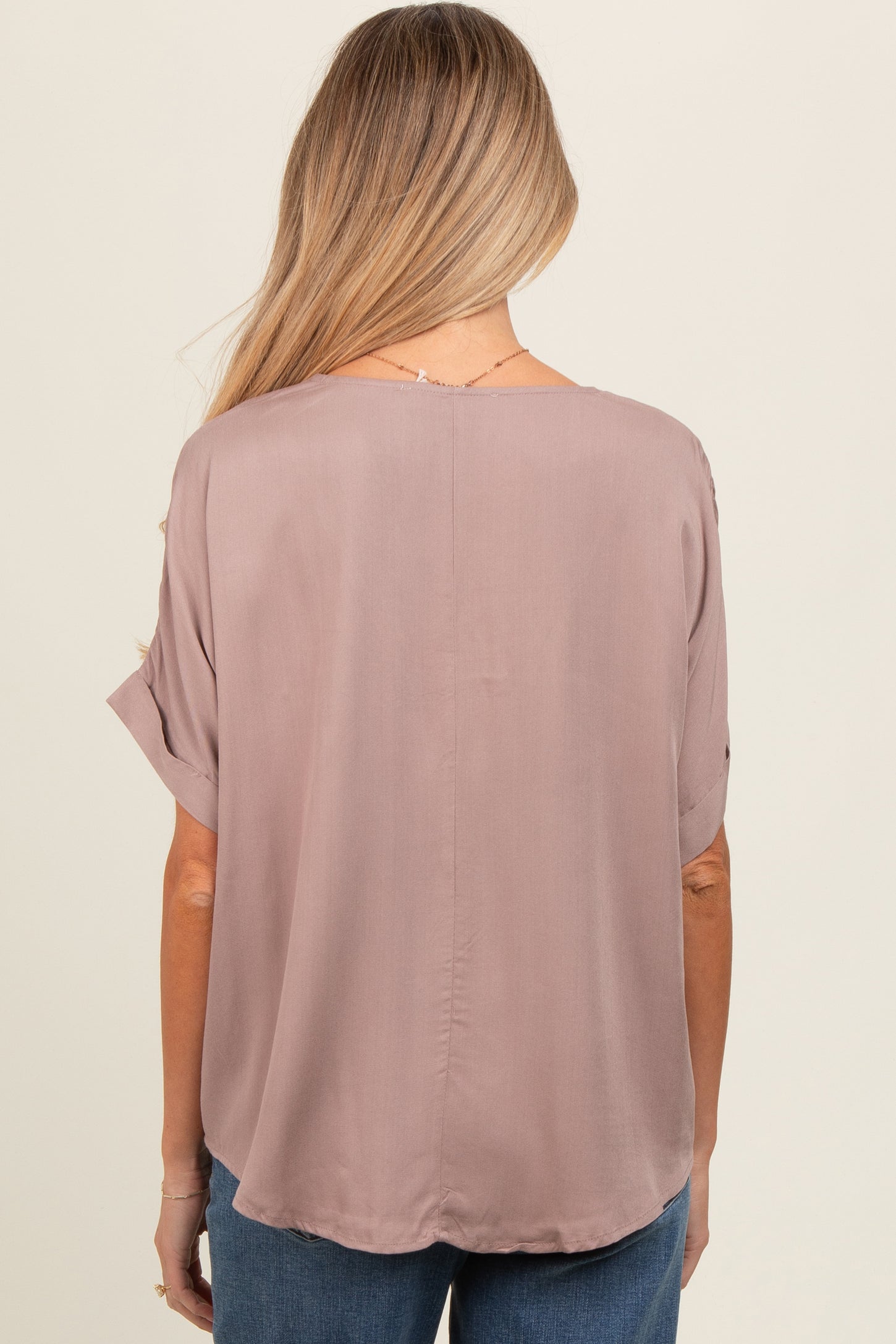 woman wearing a mauve short sleeve maternity top, featuring a relaxed fit and round hem with a smooth back design