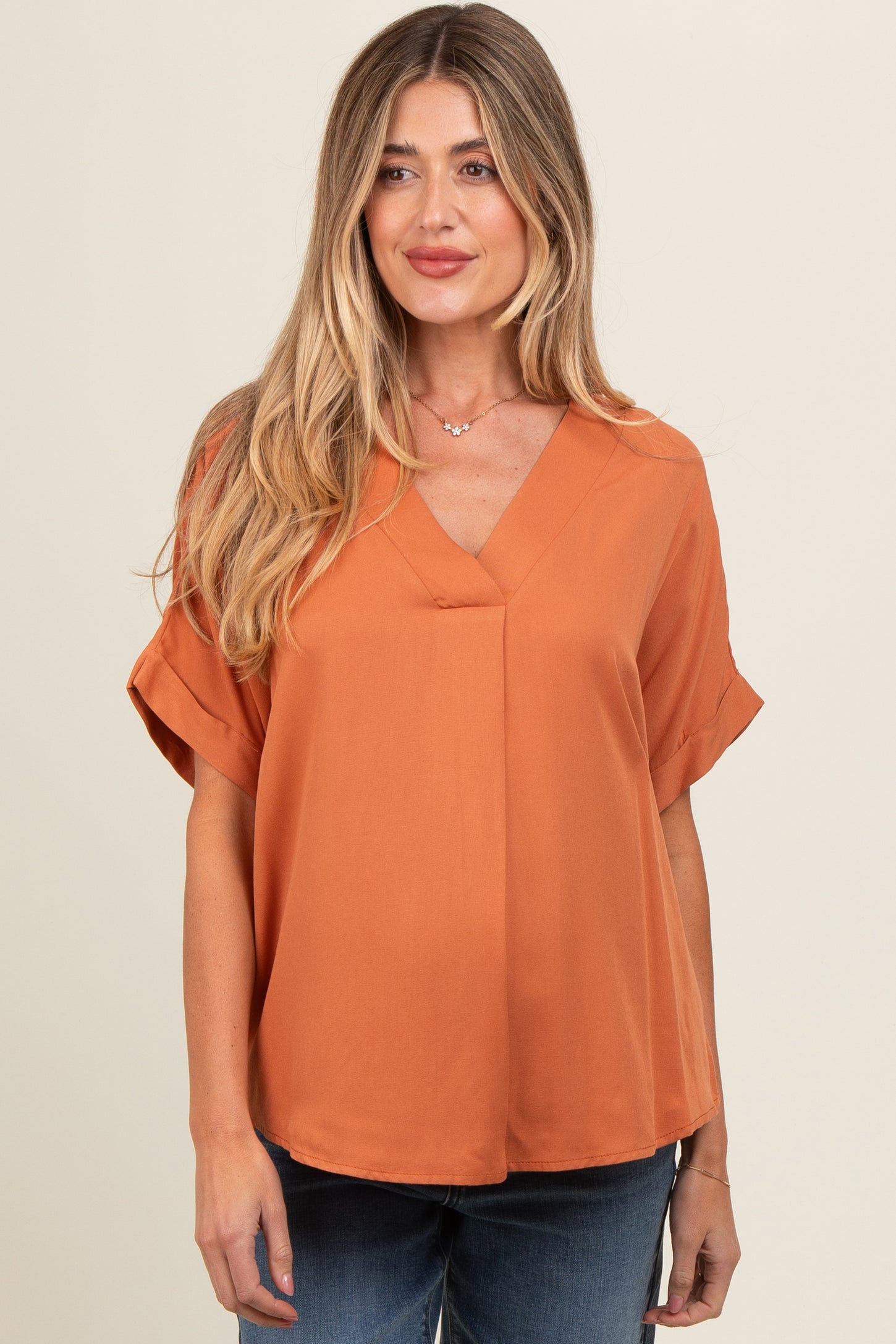 woman wearing an orange v-neck maternity top with short sleeves and a relaxed fit
