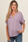 woman wearing a lavender v-neck maternity top with short sleeves and a baby bump visible