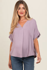 woman wearing a lavender short sleeve maternity top with a v-neck and loose fit, smiling at the camera