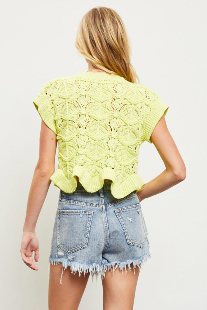 woman wearing a bright yellow short sleeve knit top with a ruffle hem and distressed denim shorts