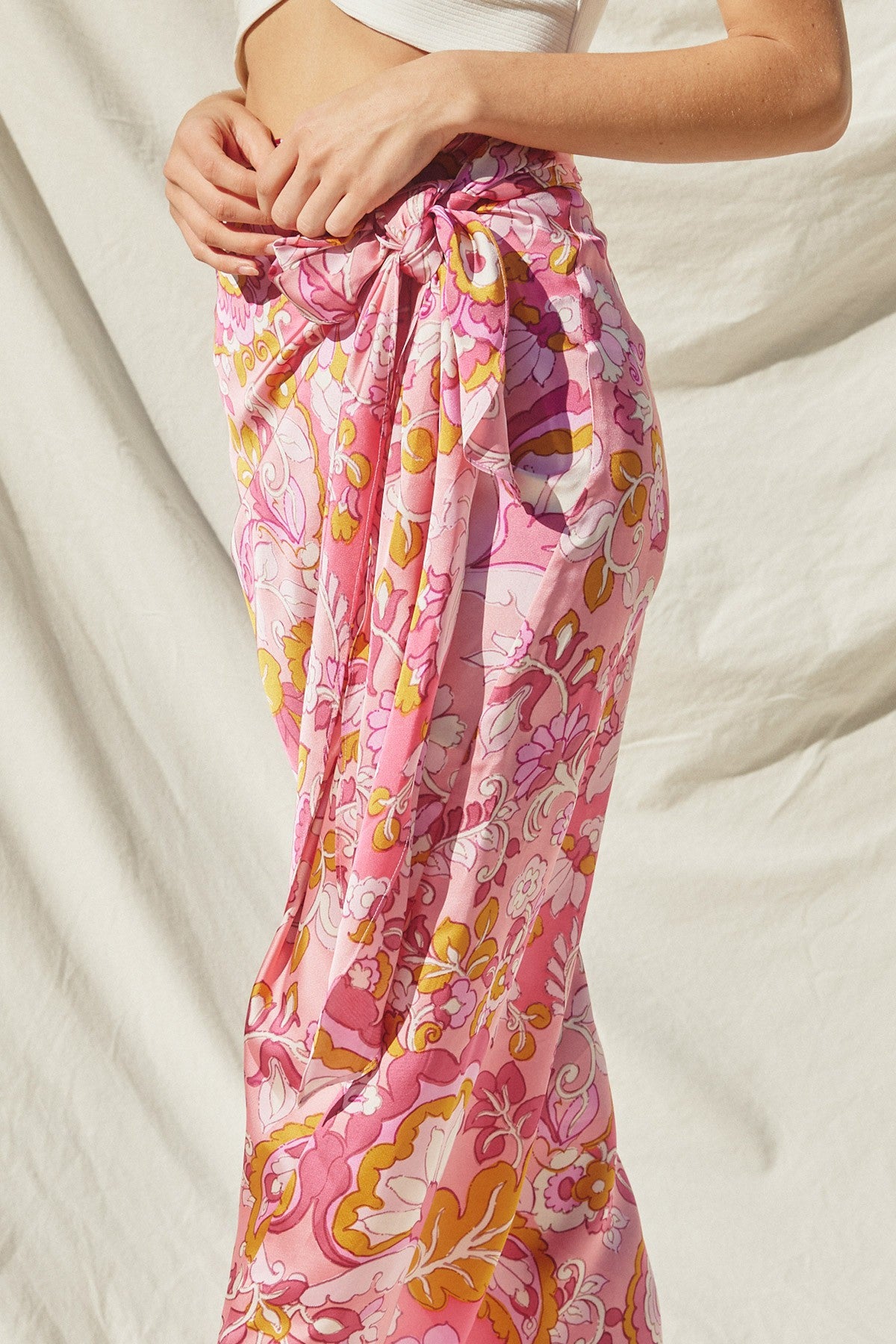 woman wearing a pink floral print maxi skirt with a tied waist detail