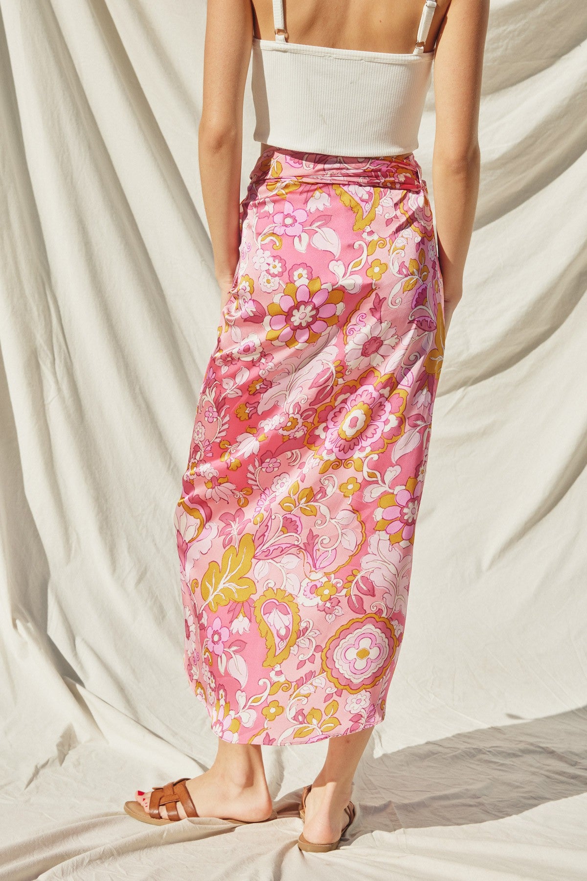 woman wearing a pink floral maxi skirt with a flowy design and a fitted waistband