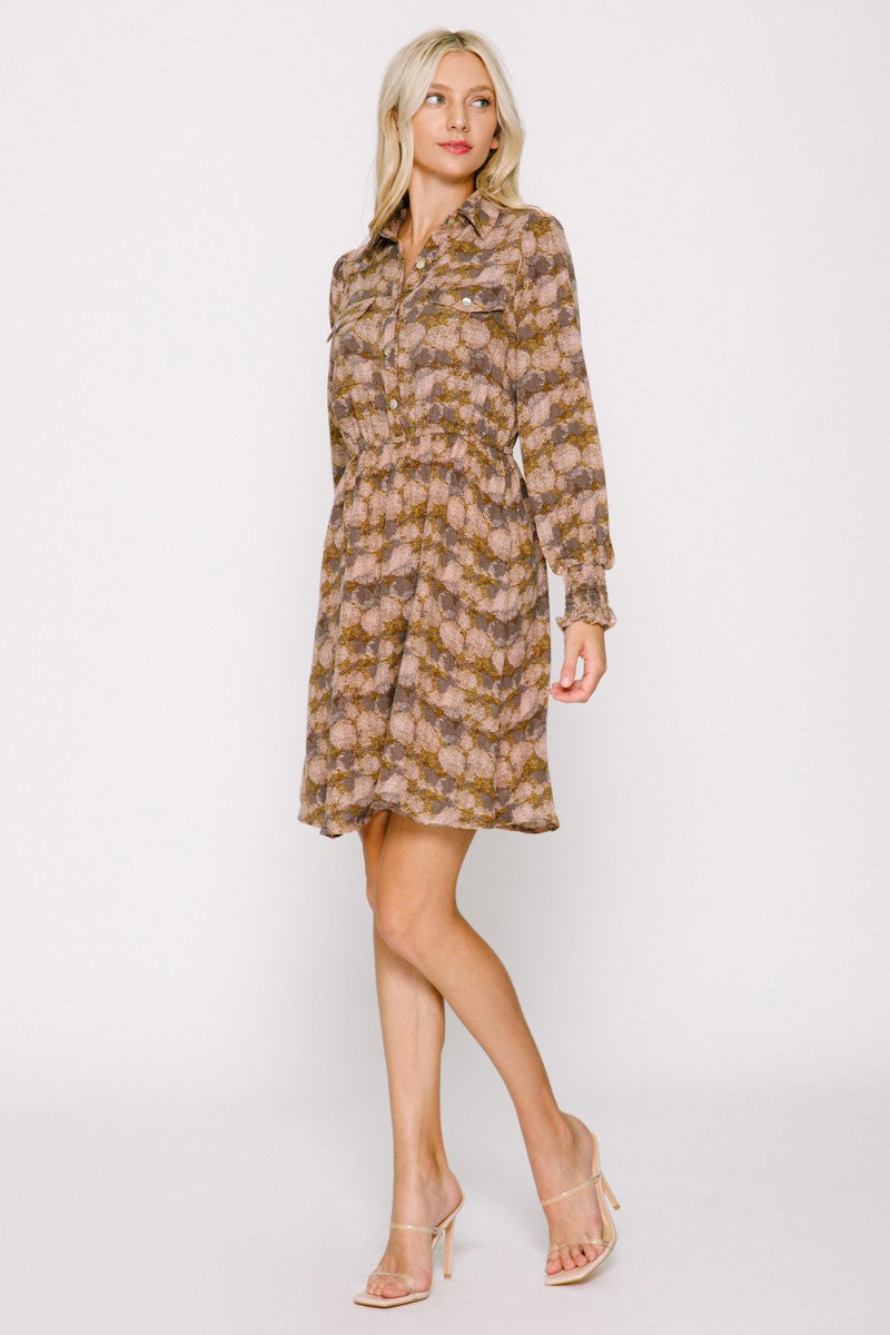 woman wearing a patterned brown and pink long sleeve shirt dress with a cinched waist and a flared skirt