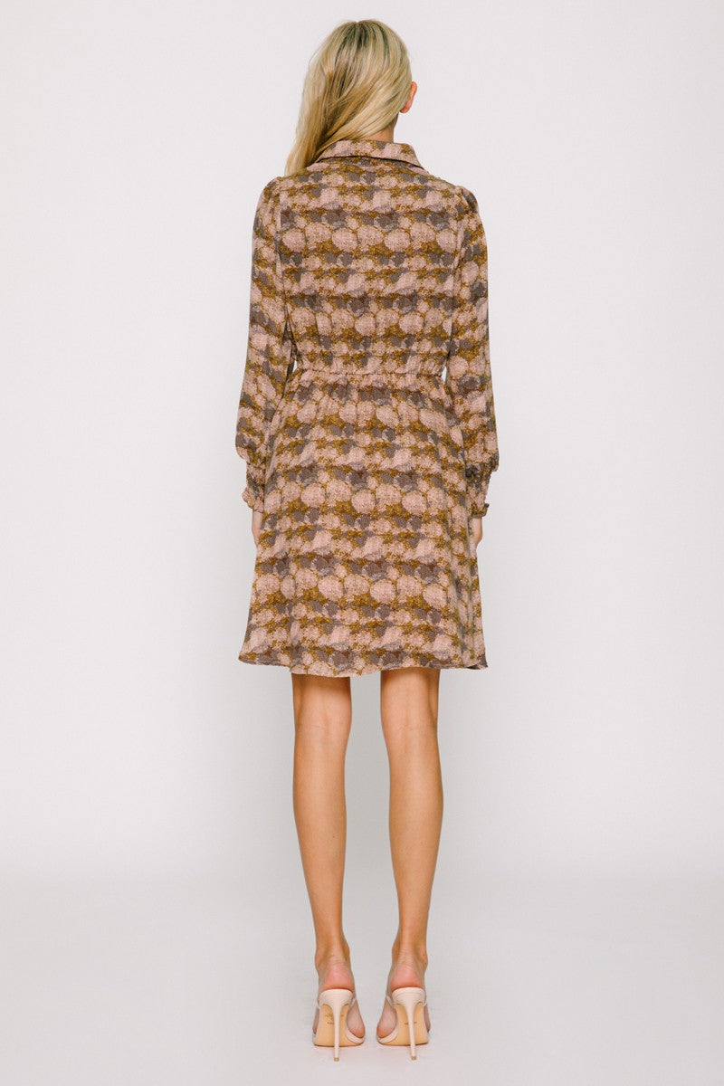 woman wearing a floral patterned brown dress with long sleeves and a tie waist, viewed from the back