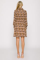 woman wearing a floral patterned brown dress with long sleeves and a tie waist, viewed from the back