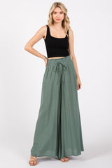 woman wearing a black ribbed crop top and green wide-leg pants with an elastic waist and drawstring