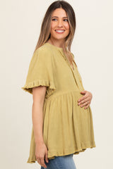 woman wearing a mustard yellow maternity top with ruffled sleeves and a baby bump visible