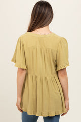 woman wearing a mustard yellow maternity top with short ruffled sleeves and a tiered hem, viewed from the back