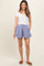 woman wearing a white short sleeve maternity top and light blue maternity shorts with side pockets