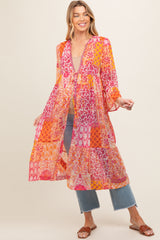 woman wearing a colorful maternity cover-up with mixed patterns and bell sleeves, styled over casual jeans and a top
