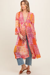 woman wearing a multicolored floral maternity kimono over a beige top and blue jeans, showing her baby bump