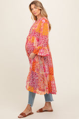 woman wearing a colorful patchwork maternity dress with long sleeves and a flowing design, showing her baby bump