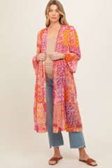 woman wearing a colorful floral print maternity kimono over a tan top and blue jeans