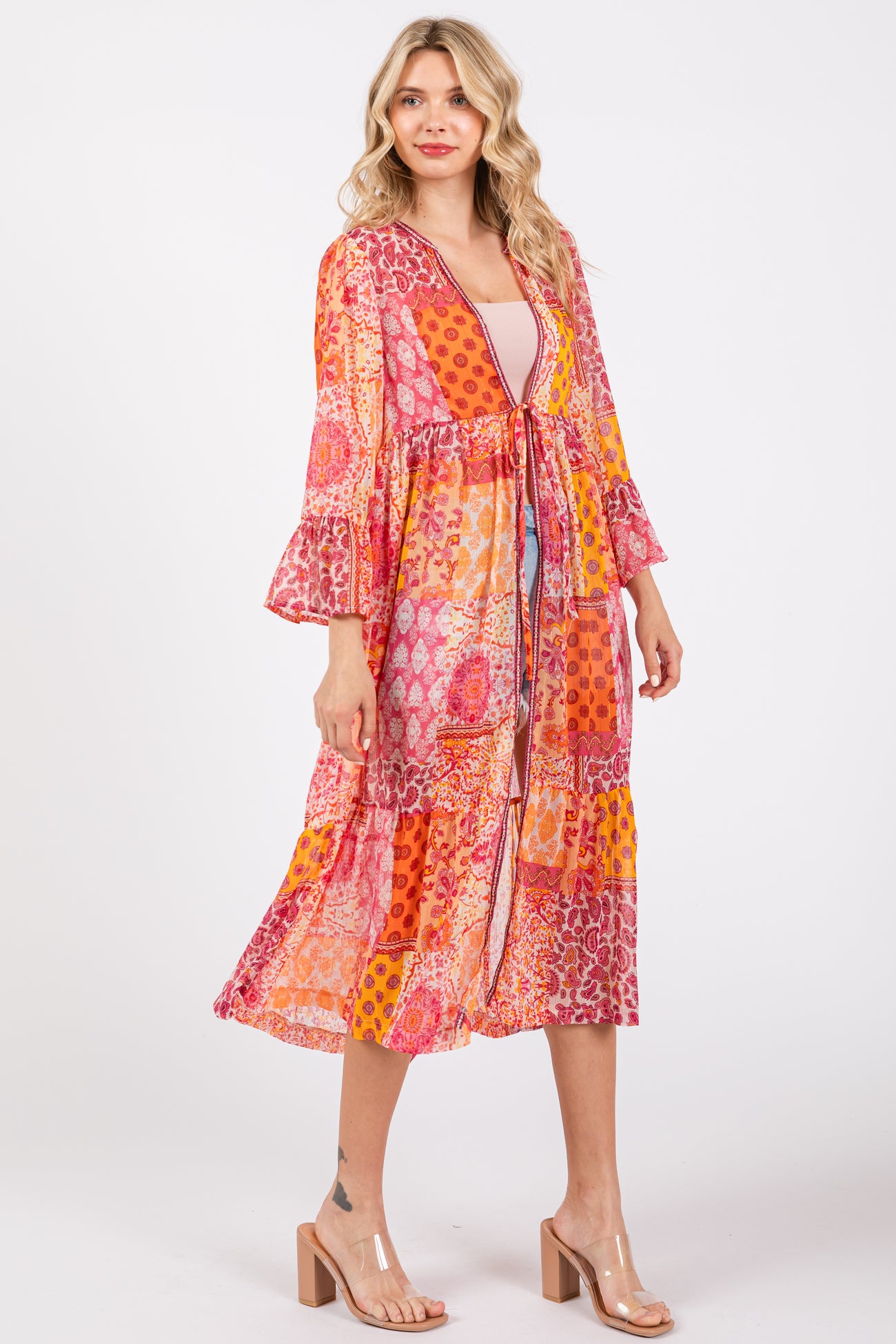 woman wearing a vibrant multi-patterned long kimono with bell sleeves and a tie waist detail