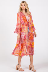 woman wearing a vibrant multi-patterned long kimono with bell sleeves and a tie waist detail