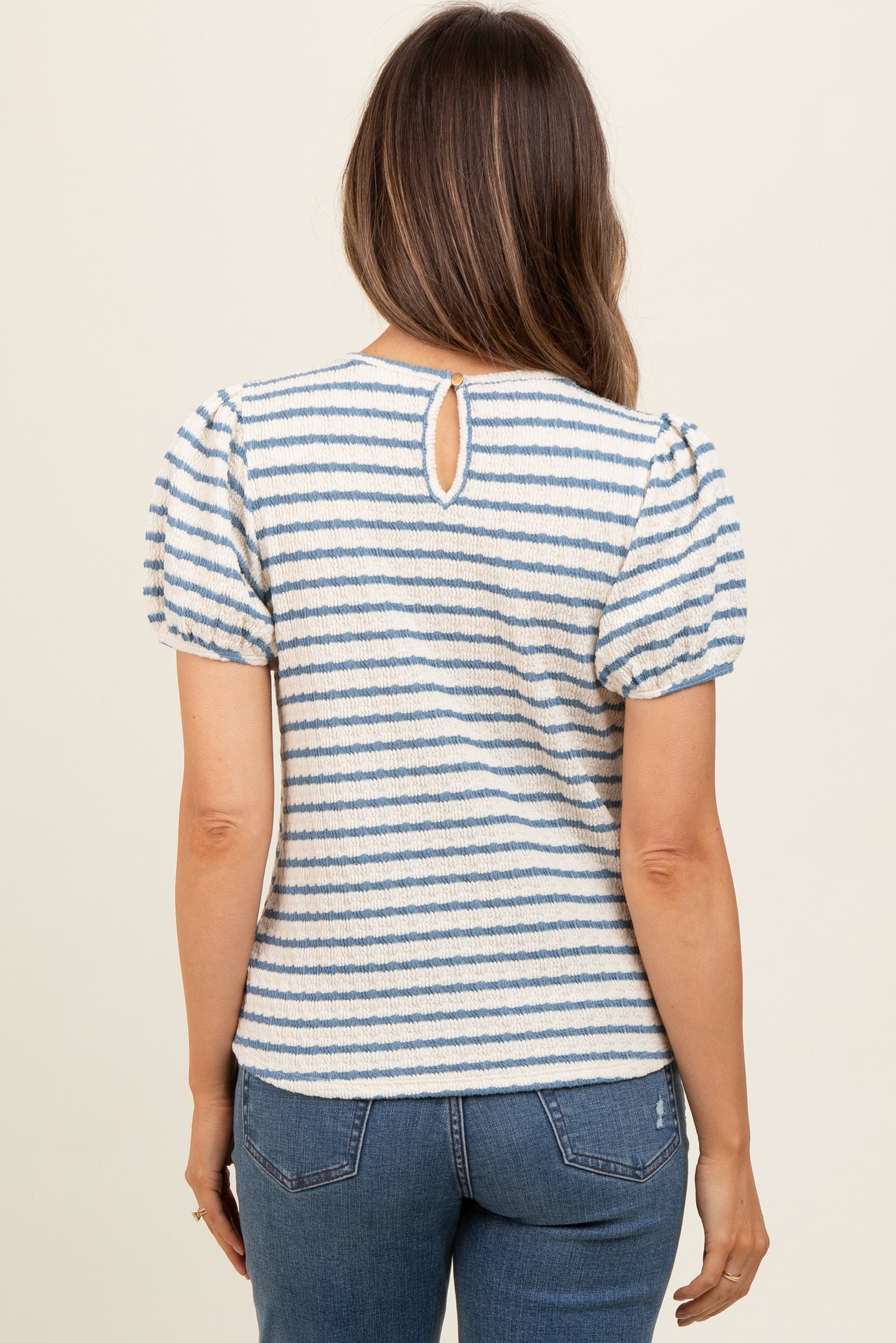 woman wearing a striped maternity top with puff sleeves and a keyhole back detail, viewed from the back