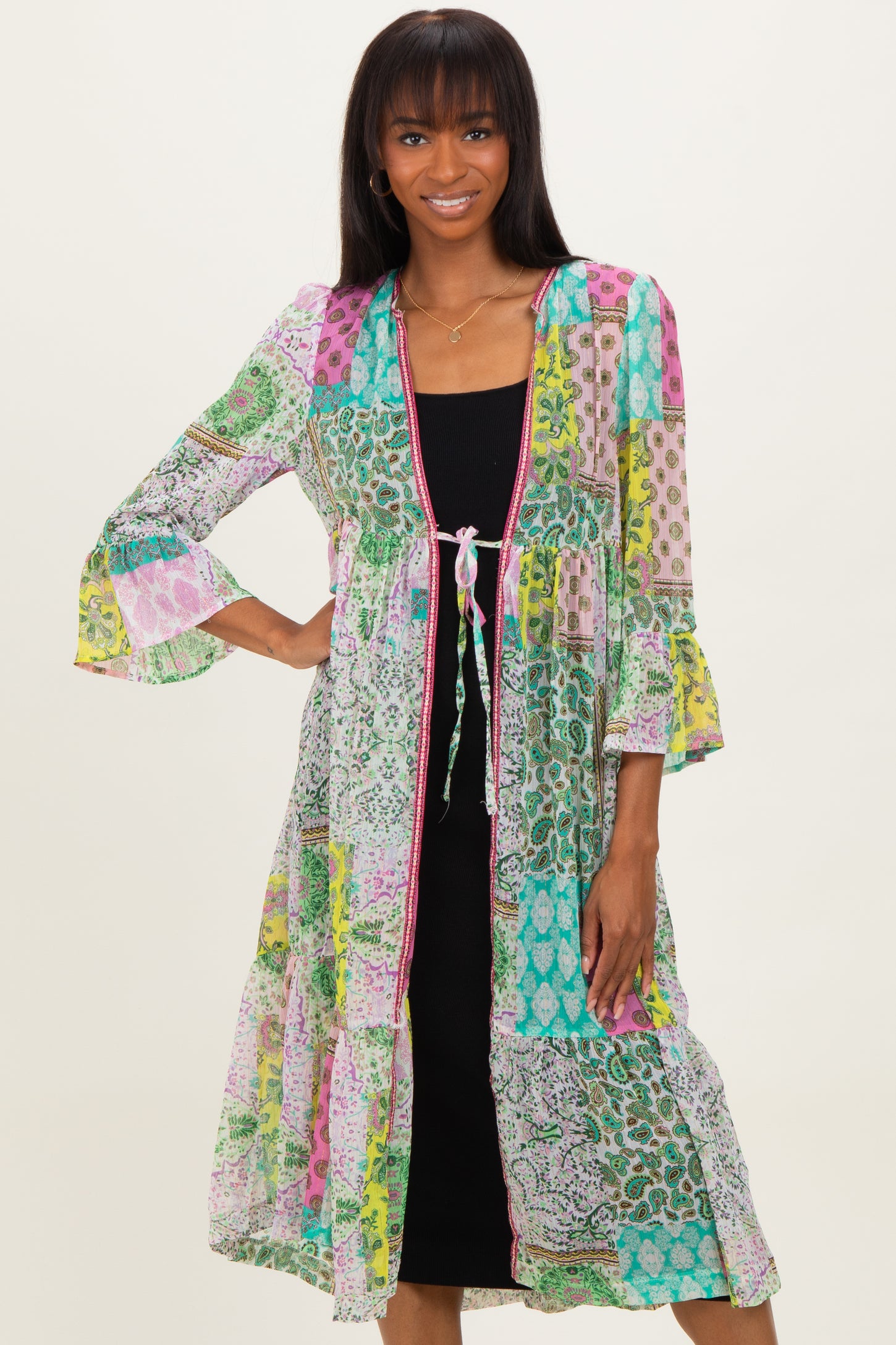 woman wearing a colorful patterned long kimono cardigan over a black fitted dress with bell sleeves