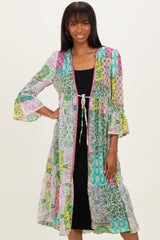 woman wearing a colorful patterned long kimono cardigan over a black fitted dress with bell sleeves