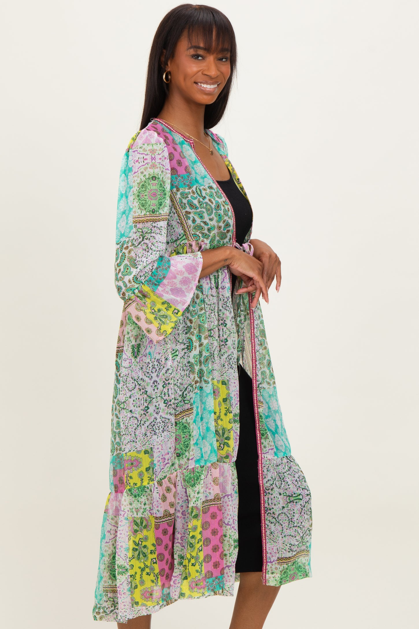 woman wearing a colorful long kimono with floral patterns over a black dress and smiling