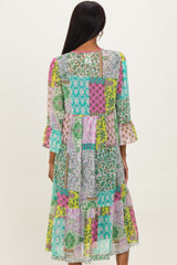 woman wearing a colorful patchwork midi dress with flared sleeves and a tiered hem, shown from the back