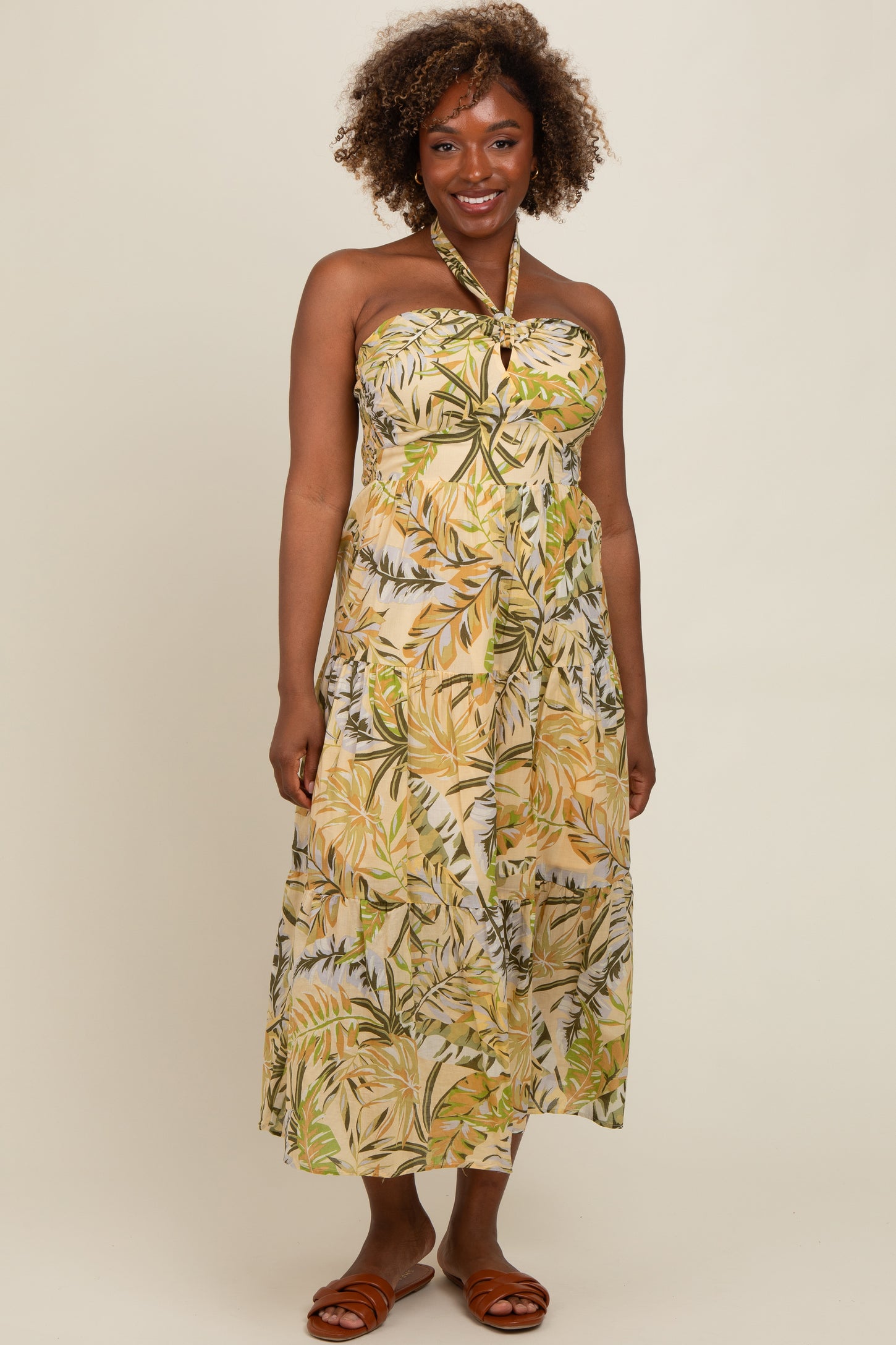 woman wearing a strapless maxi dress with a tropical leaf print in green and yellow